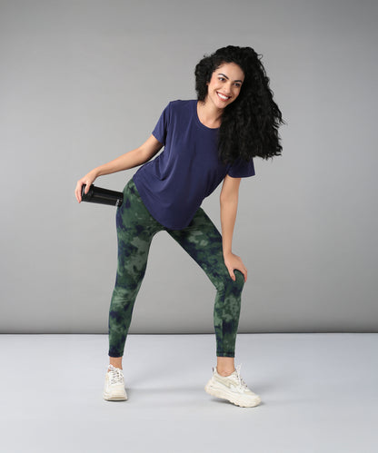 Smiling woman wearing the Functional - Blue Soft T Shirt made from durable, comfortable materials, holding a water bottle and posing against a plain grey background.
