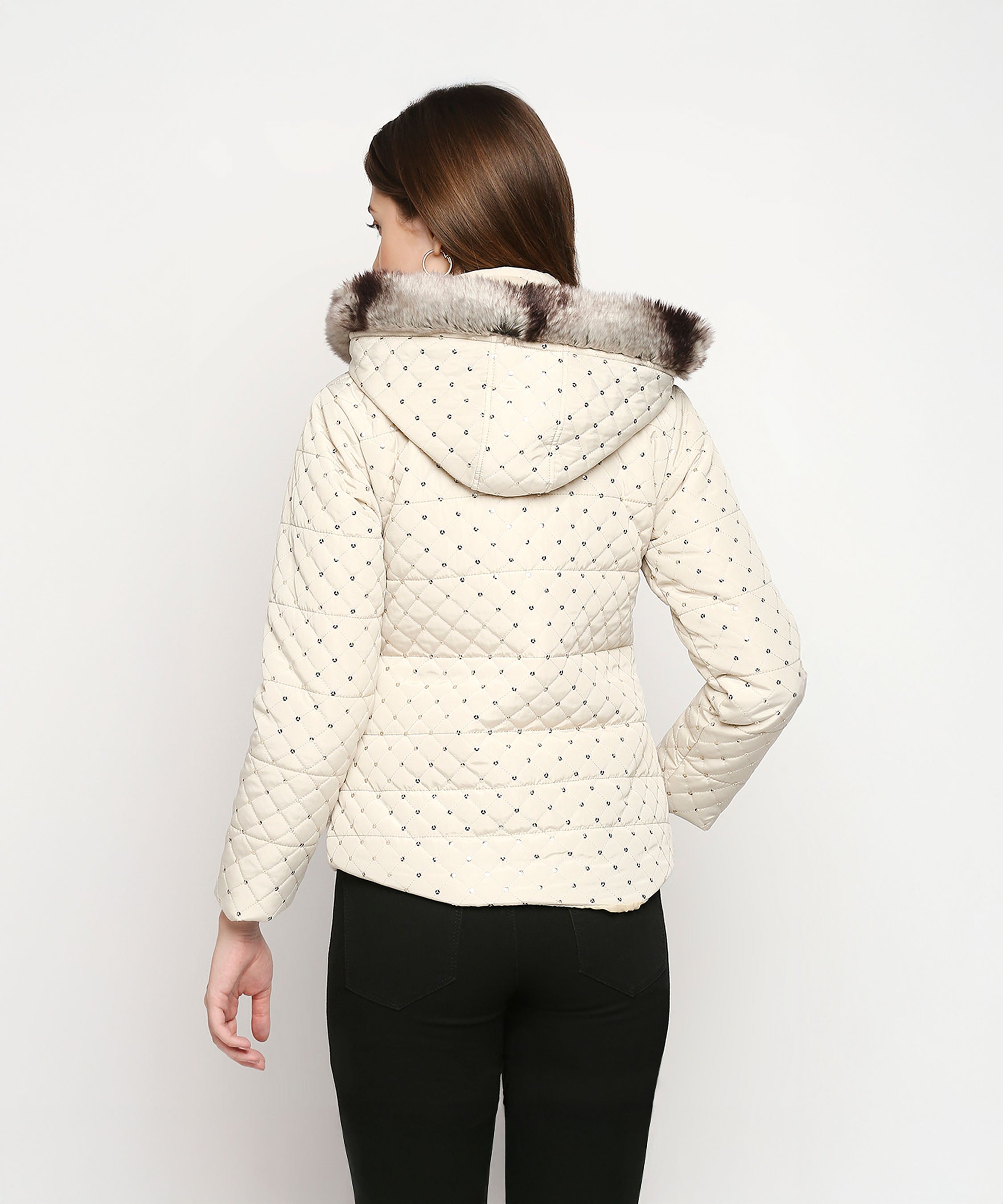 A woman faces away, wearing an Off White Mid Length High Collar Puffer Jacket with a detachable fur hoodie and black pants against a white background.