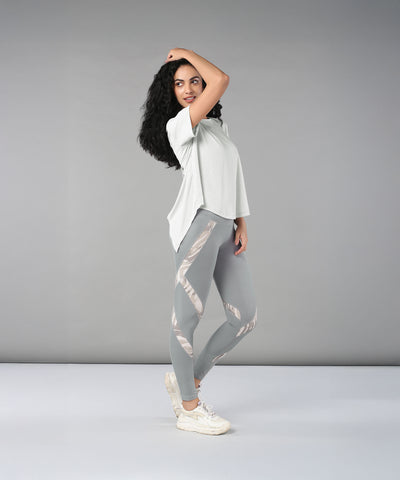 Woman wearing the Grey Top with Patched Legging, made from super soft fabric, poses confidently against a plain grey background.