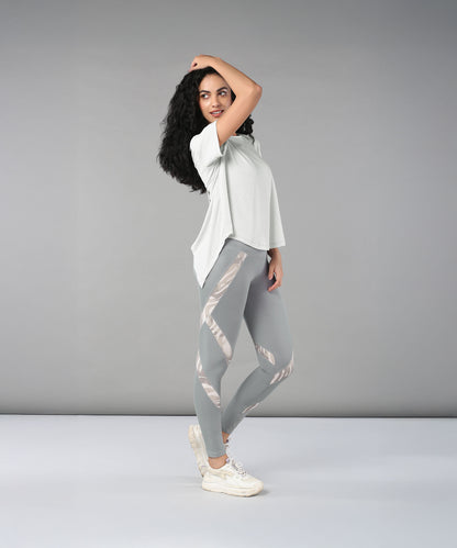 Woman wearing the Grey Top with Patched Legging, made from super soft fabric, poses confidently against a plain grey background.