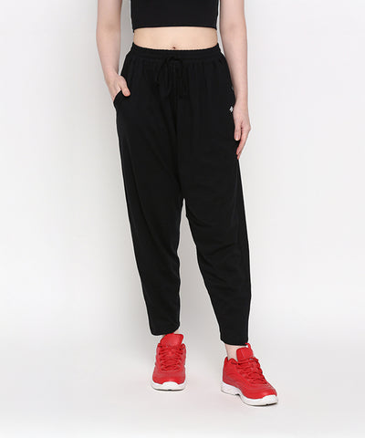 A person is wearing Yoga Pants in black with a relaxed fit, paired with a black crop top and red sneakers, standing against a white background.