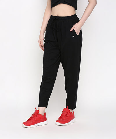 A person is wearing Yoga Pants in black, paired with a black crop top and red sneakers, standing against a white background.