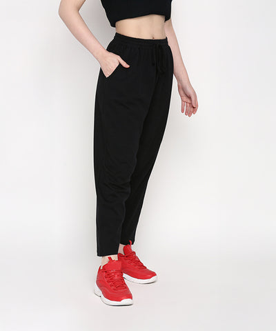 A person in Yoga Pants stands against a white background, one hand in their pocket, paired with red sneakers.