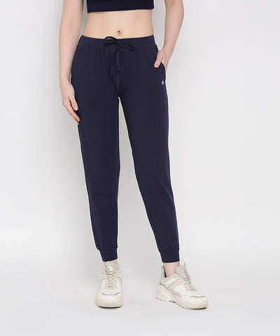 Woman wearing Blue Classic Joggers TLC04, white sneakers, and a black crop top, standing against a white background.