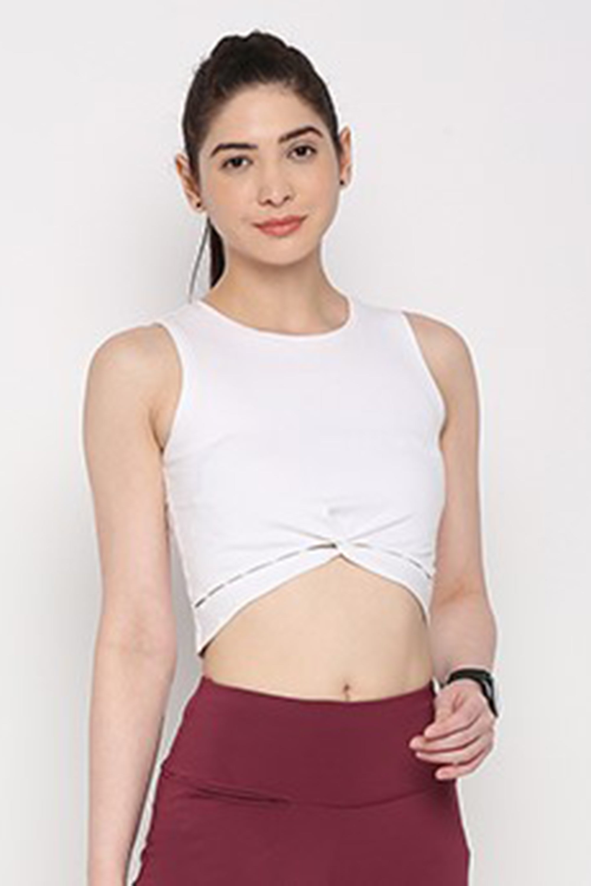 Woman in a White Twisted Crop Top and maroon leggings, standing against a plain background.