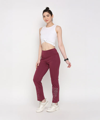 Woman in a white crop top and Tuna Active Wine Color Boot Cut Pants, posing against a plain white background.