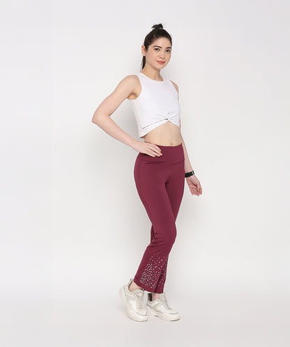 Woman posing in a White Twisted Crop Top and maroon embellished pants against a plain background.