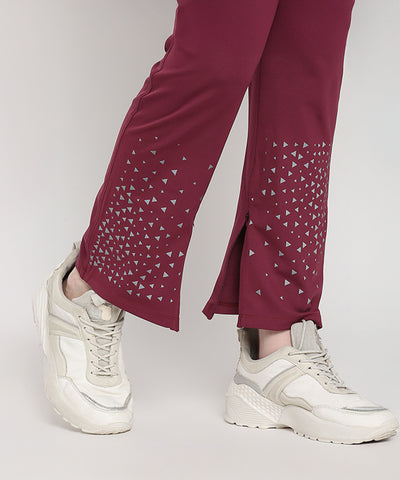 Model wears Tuna Active Wine Color Boot Cut Pants featuring small triangle patterns with white sneakers, standing against a light background.