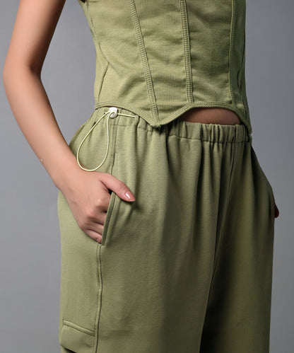 Model in the Olive Corset Crop - Top with Parachute Pants, posing with one hand in their pocket.