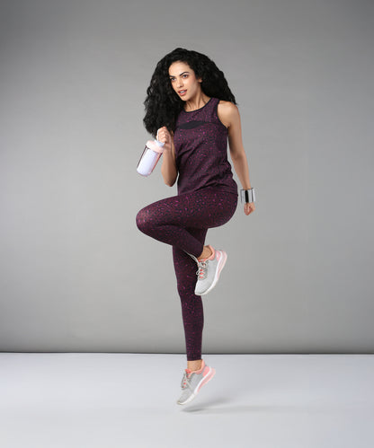 A woman wearing Pink Animal Print Leggings poses on one leg with a shaker bottle against a plain gray background.