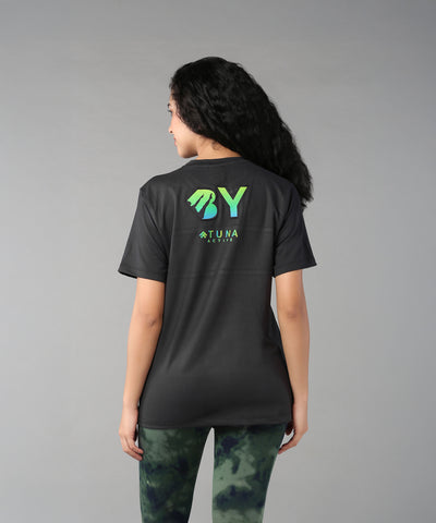A woman with long curly hair, seen from behind, wears the Positive Body Image T Shirt—a black basic tee with green text and half sleeves—embracing positive body image.
