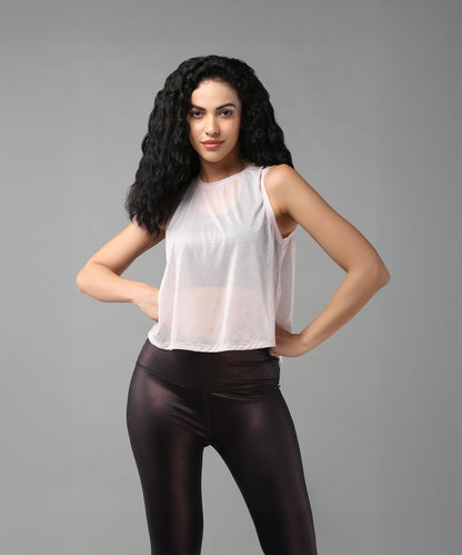 Woman with long curly hair poses confidently in a Powder Pink Sheer Top and black leggings.