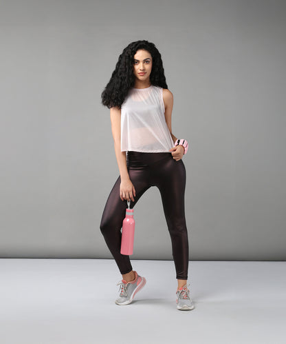 Woman wearing the Powder Pink Sheer Top and workout clothes holds a pink water bottle, standing against a plain gray background.