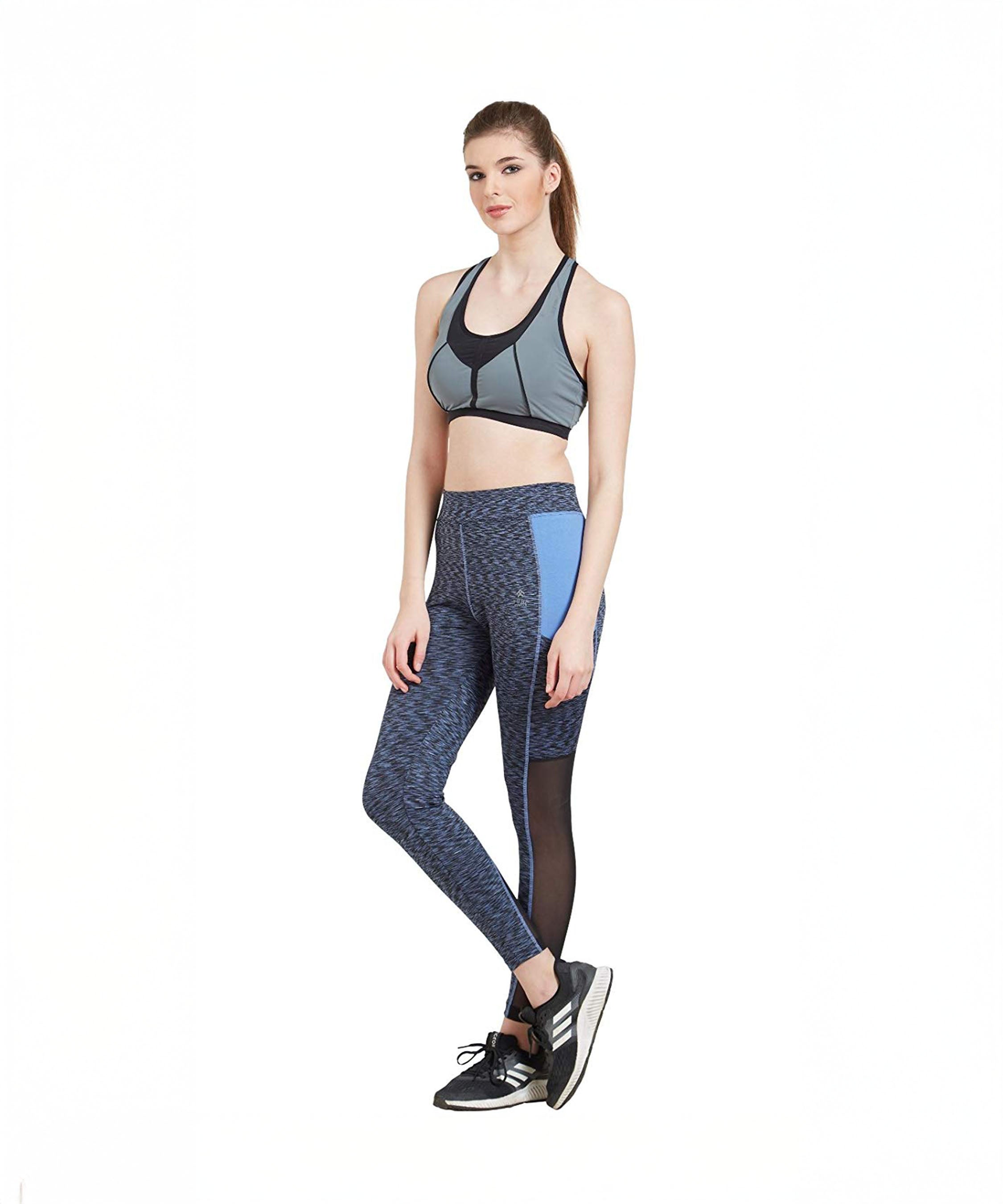 Woman in athletic wear, including a sports bra and Blue Poly Cotton Lycra Printed Slim Fit Track Pant for Women, standing with one leg crossed over the other.