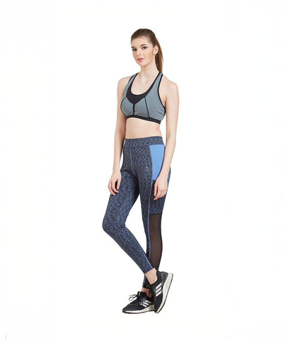 Woman in athletic wear, including a sports bra and Blue Poly Cotton Lycra Printed Slim Fit Track Pant for Women, standing with one leg crossed over the other.