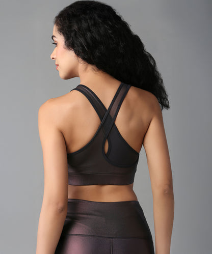 A woman with curly hair is shown from the back against a plain background, wearing the Radiant Maroon Shimmer Sports Bra and matching leggings for high support.