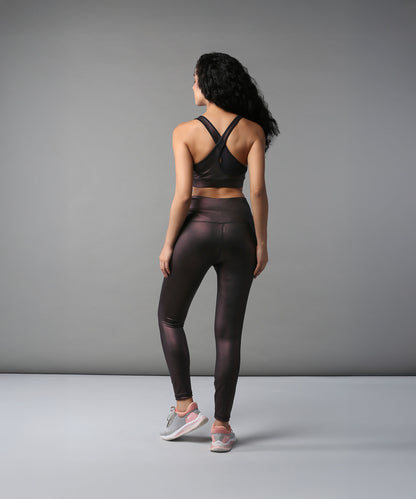 Woman in the Radiant Maroon Shimmer Work out Ensemble stands with her back to the camera against a gray background.