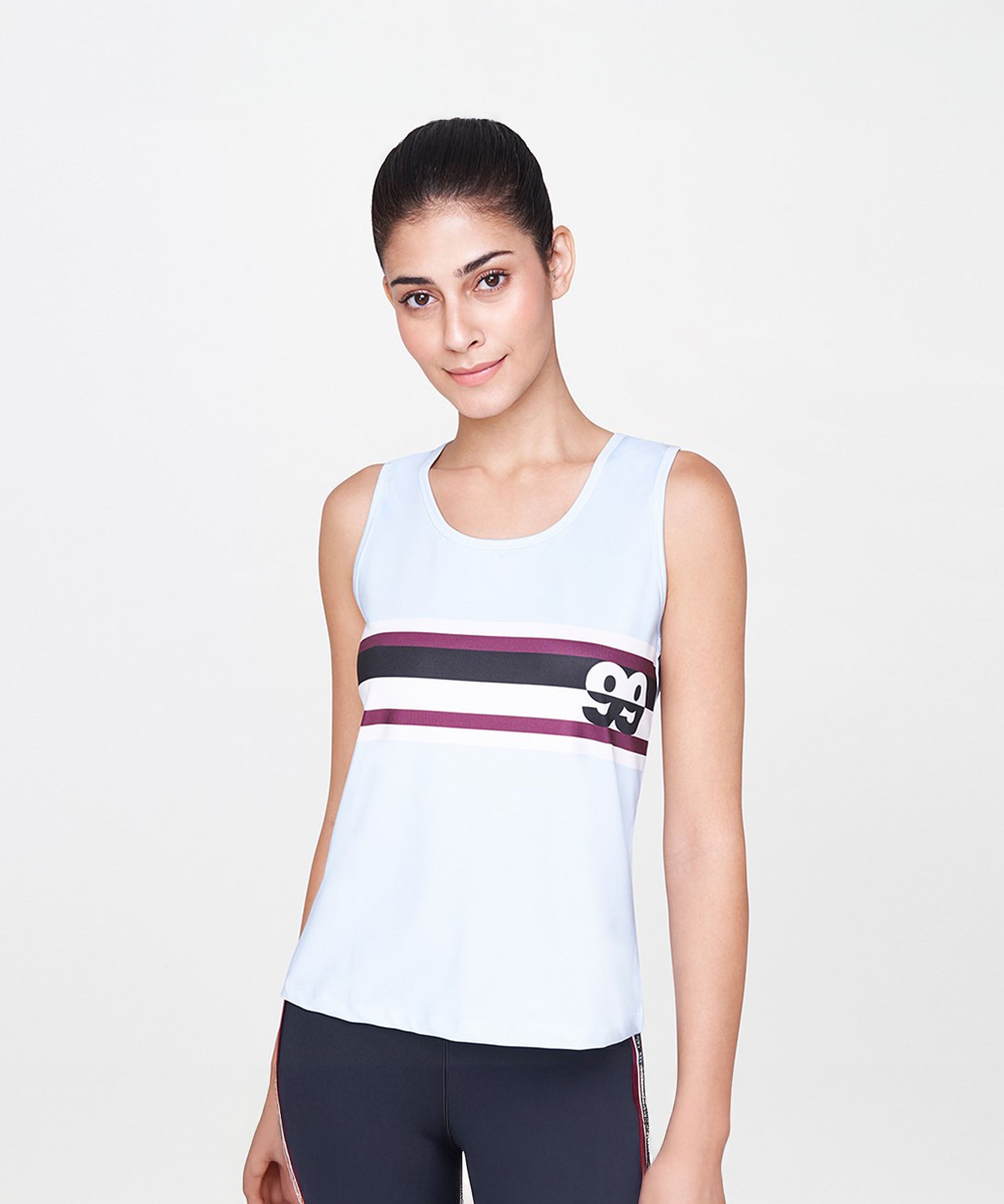 A woman models the Powder Blue T-Shirt, a sleeveless top with horizontal stripes and a graphic, featuring a relaxed fit, against a plain background.