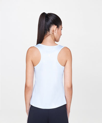 A woman with a long dark ponytail is seen from the back, wearing the Powder Blue T-Shirt in a relaxed, sleeveless style against a plain background.