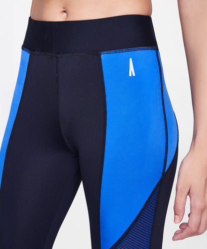 Close-up of a person wearing Indigo Leggings, deep blue in color, featuring a small white logo on the hip.