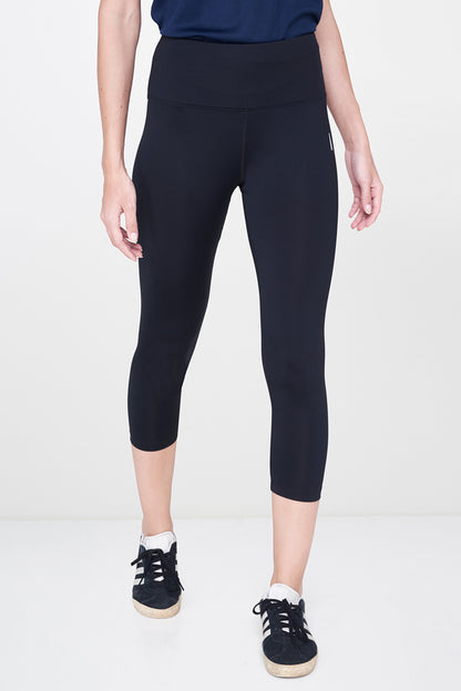 Wearing Black Leggings and white sneakers with white soles paired with a navy top, this must-have look stands out against a white background.
