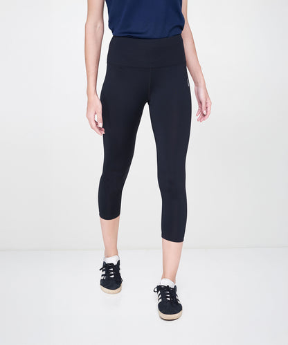 A person wearing Black Leggings with a high-rise waistband, paired with a navy shirt and black sneakers, stands against a white background.