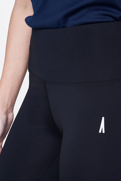 A person wearing Black Leggings and a navy top, styled with classic white sneakers—a wardrobe essential—shown from waist to mid-thigh.