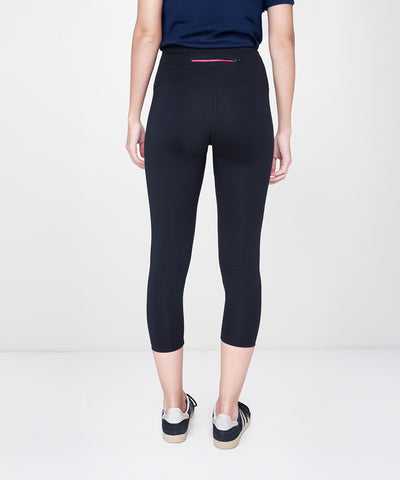 Person standing with their back to the camera, wearing Black Leggings featuring a high-rise waistband, paired with a navy shirt and sneakers.