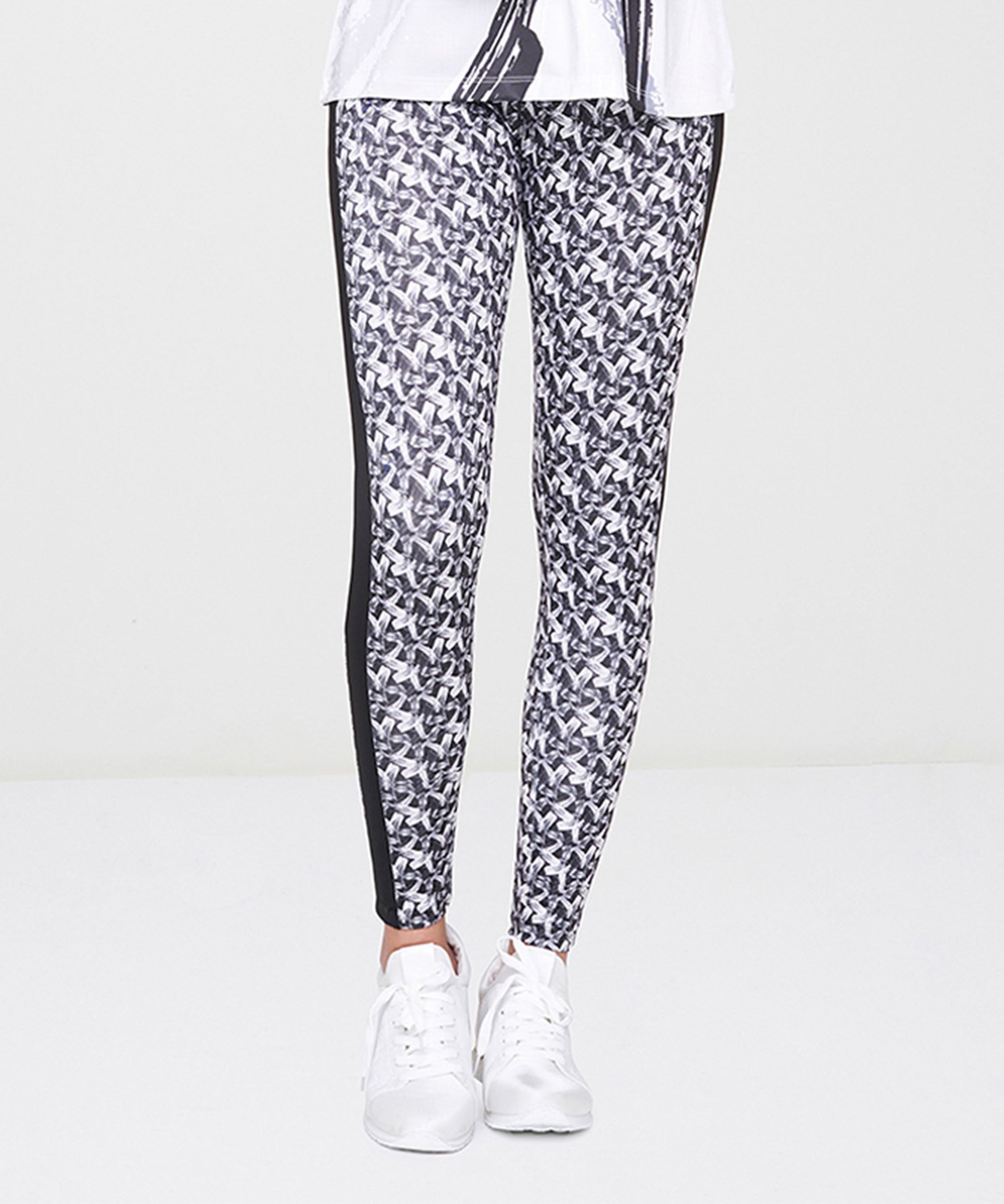 Person wearing White Printed Leggings with a black and white pattern, paired with white sneakers, standing on a white surface.
