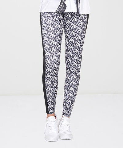 Person wearing White Printed Leggings with a black and white pattern, paired with white sneakers, standing on a white surface.
