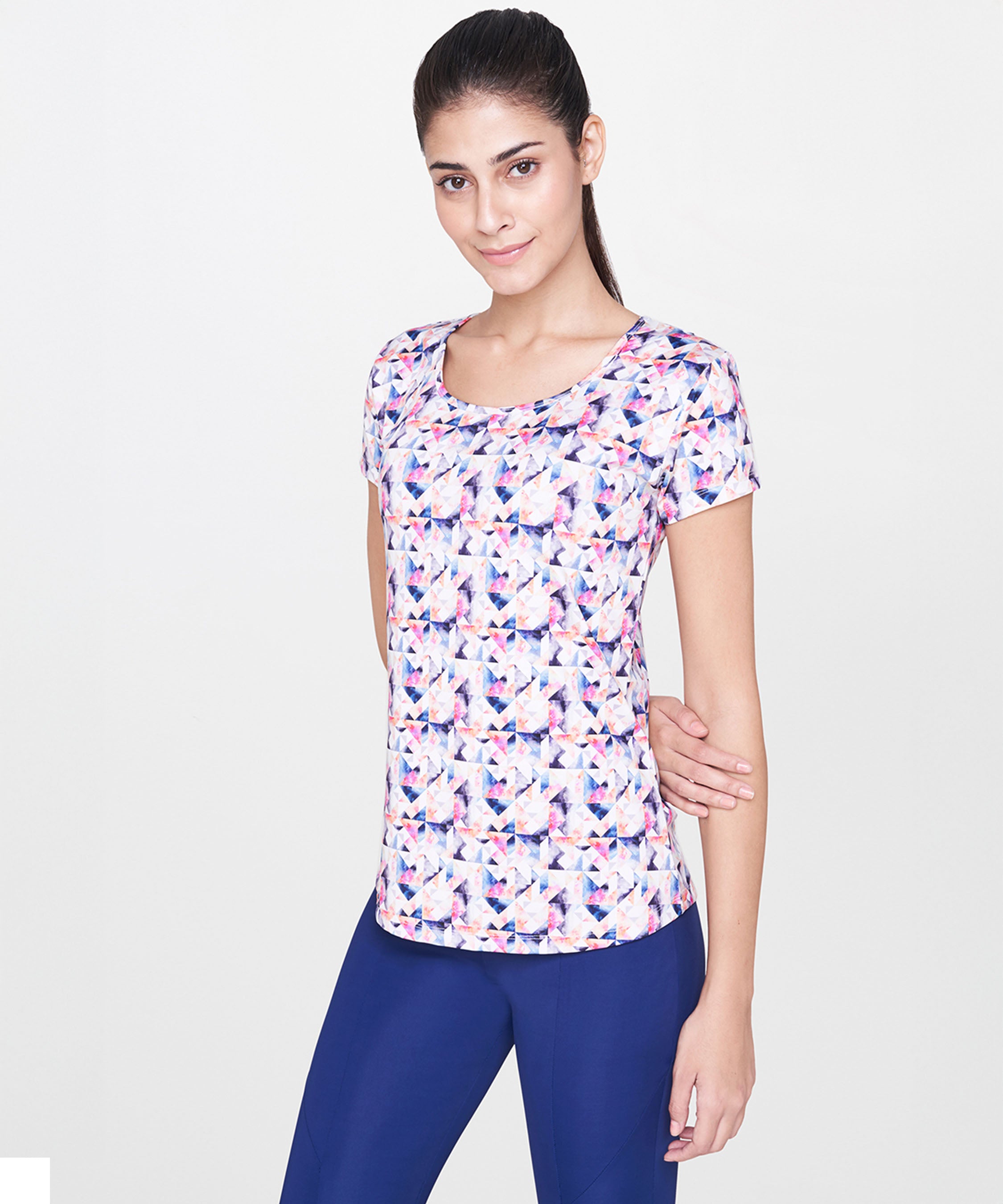 Woman wearing a White Multicolour Printed Top and blue pants, standing against a plain white background.