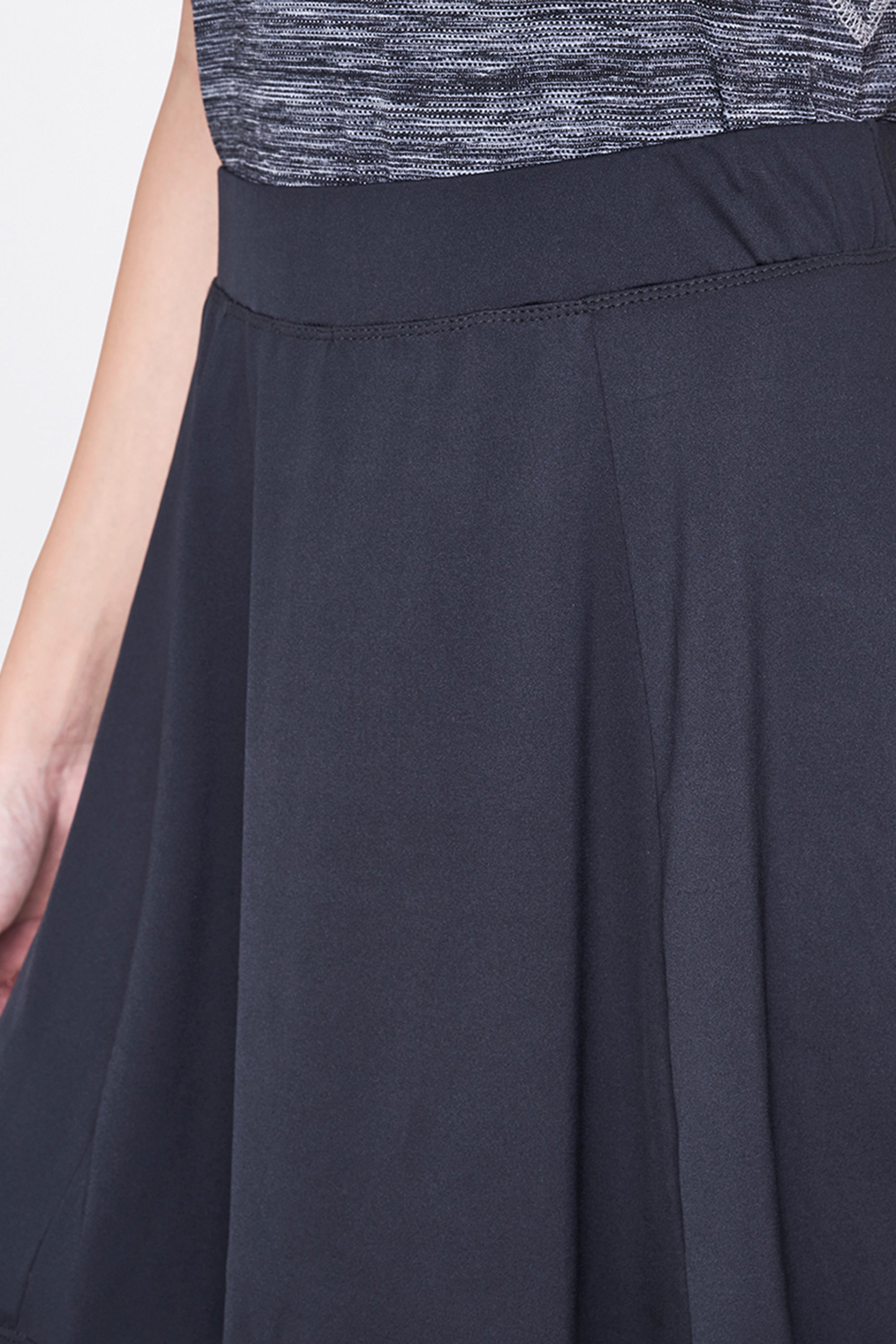 A person wearing a Grey Skirt; only the waist and part of the hand are visible.