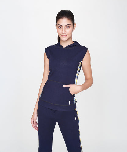 A woman models the Navy Blue Sleeveless Hoodie with matching pants against a plain white background, highlighting this breathable, athletic hoodie that’s ideal for workouts.