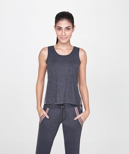 Woman smiles with hands in pockets, wearing a charcoal grey sleeveless tank top and joggers (Grey Sleeveless Tank Top) against a white background. SS19ATHAND34.