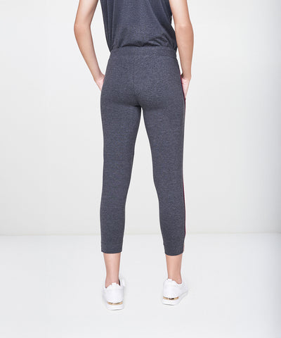 A person is wearing the Dark Grey Milange Tank Top With Joggers, paired with white sneakers and standing with hands behind their back.