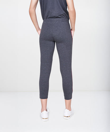 A person is wearing the Dark Grey Milange Tank Top With Joggers, paired with white sneakers and standing with hands behind their back.