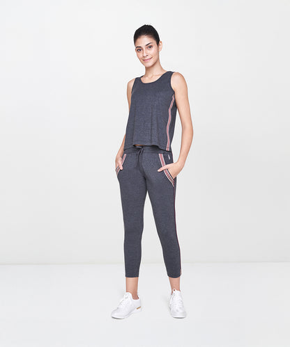 Woman wearing Grey Joggers With Pockets, paired with a dark gray sleeveless top and white sneakers, standing and smiling.