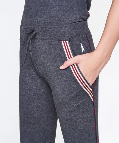 Model wearing Dark Grey Milange Tank Top With Joggers featuring striped pocket detail, drawstring waist, and hand in pocket.