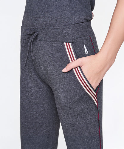 Model wearing Dark Grey Milange Tank Top With Joggers featuring striped pocket detail, drawstring waist, and hand in pocket.