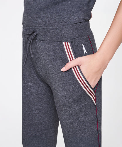 A person wears Grey Joggers With Pockets, featuring red and white side stripe details, with hands casually in the pockets.