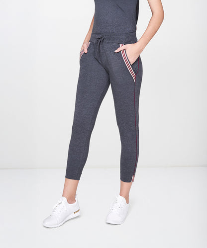 A person wears the Dark Grey Milange Tank Top With Joggers, paired with white sneakers, standing against a plain background.