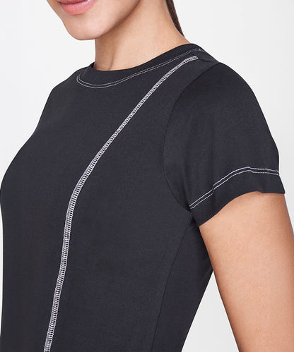 Woman wearing the Black T-Shirt, featuring a fitted cut and white stitching detail, shown from shoulder to mid-torso—a versatile staple for casual outfits.