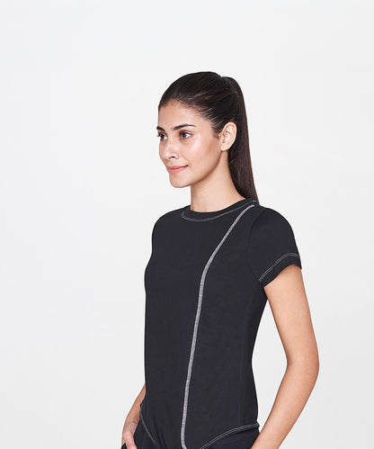 A woman with long dark hair in a ponytail wears the Black T-Shirt, a classic wardrobe staple, while standing against a plain white background.