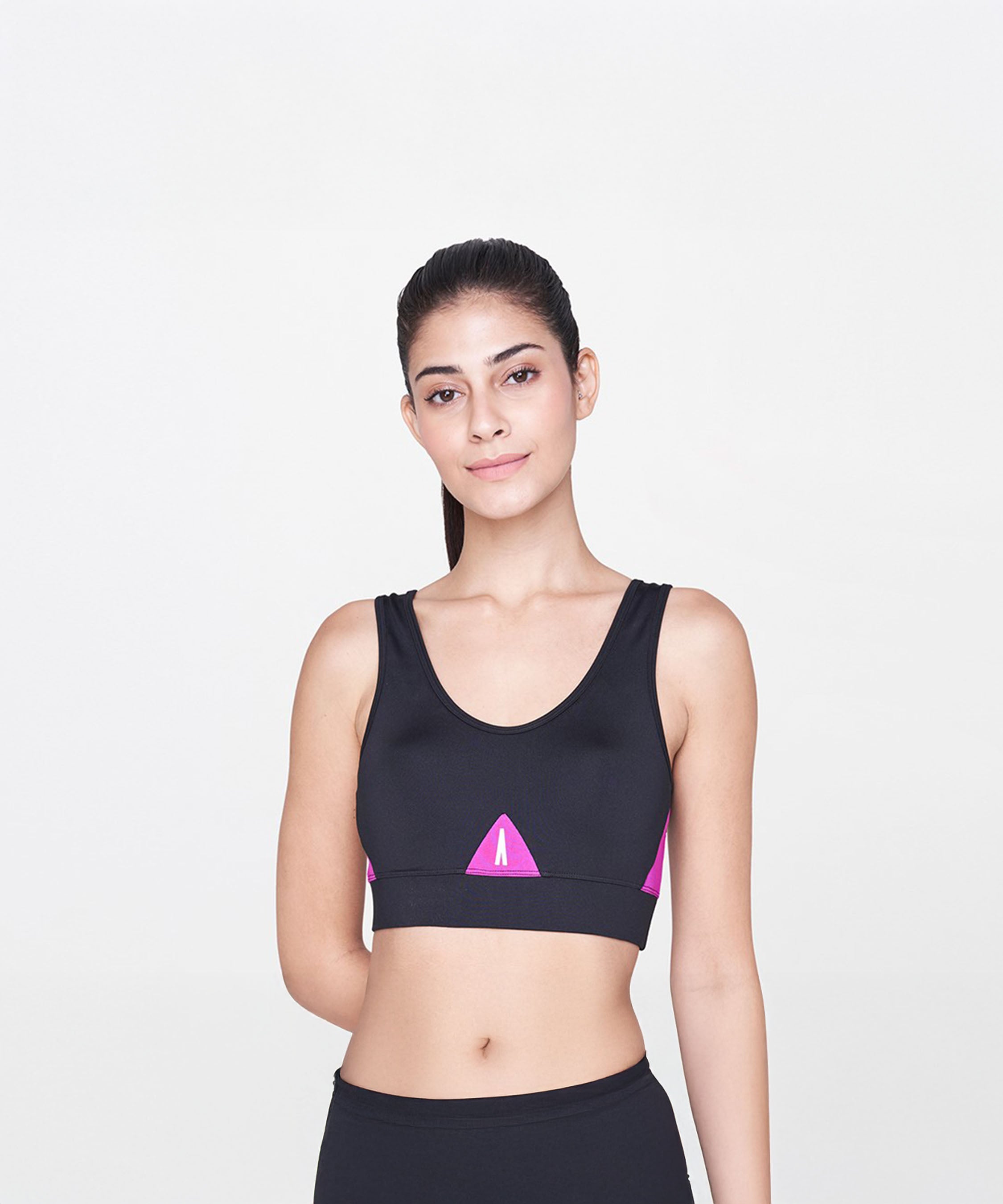 A woman models the Black and Pink Sports Bra, featuring vibrant pink accents, against a plain white background.