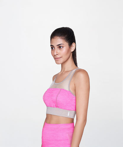 A woman models the Pink Sports Netted Bra, standing sideways in matching leggings against a plain white background to showcase the stylish activewear.