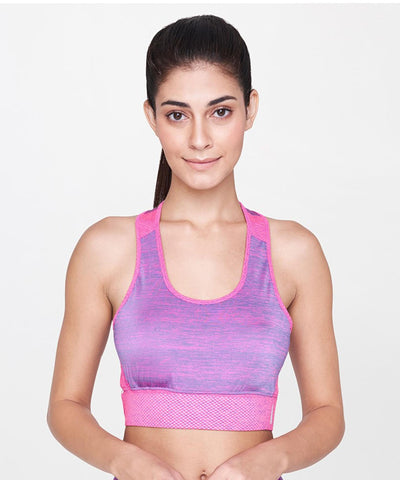 Woman with long dark hair in a ponytail wears the Pink Bra, a supportive pink sports bra, standing against a plain background.