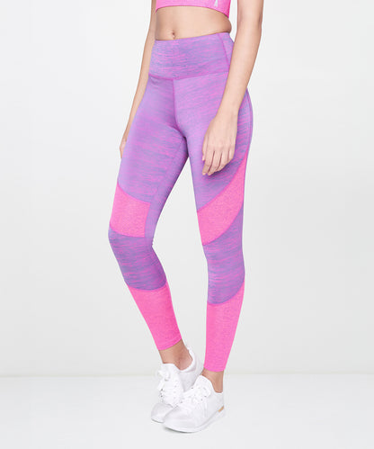 A woman stands against a plain white background wearing Pink Leggings and white sneakers.