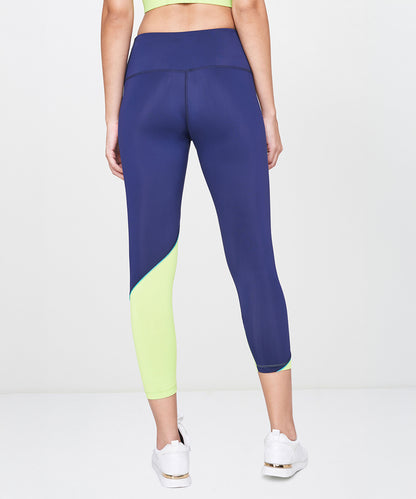 Person wearing Blue and Neon Green Leggings, white sneakers, and a green crop top, shown from the back.