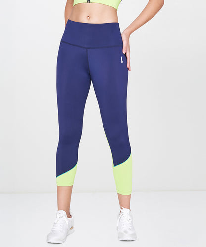Woman wearing Blue and Neon Green Leggings, white sneakers, and a cropped lime green top.