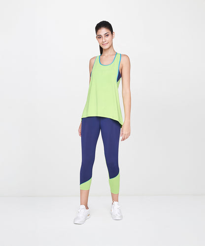 Model wears the Lime Tank Top With Leggings and white sneakers, standing against a plain white background.